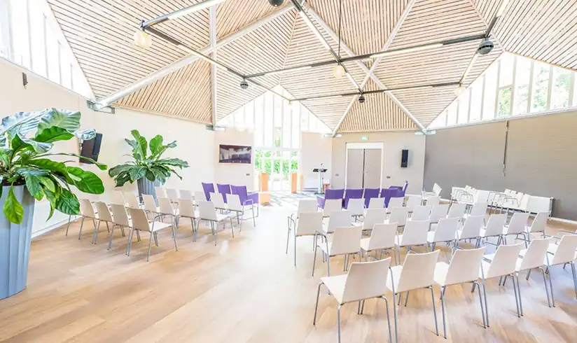 Grote zaal met meerdere rijen witte en paarse stoelen